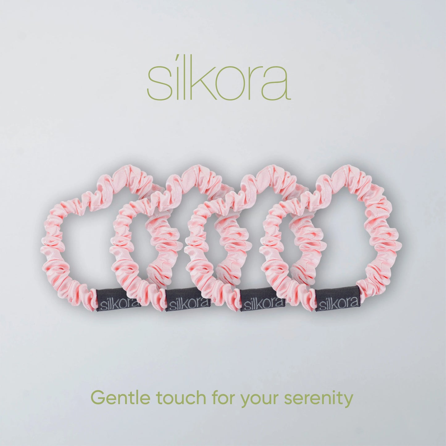 Vier kleine Silkora scrunchies in lotus roze op een lichte achtergrond met het Silkora-logo en de tekst "Gentle touch for your serenity".